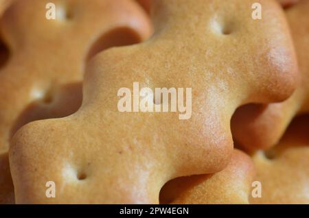 A huge bunch of salted biscuits of small sizes close-up. Macro shot of a large amount of salt cracker in golden yellow tones Stock Photo