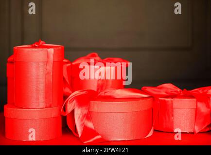 Heap of red gift boxes and golden baubles placed on table against black wall on Christmas day Stock Photo