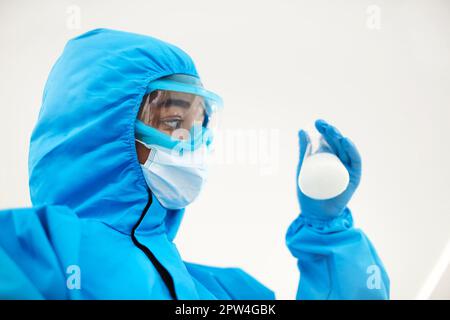 Female lab scientist examining samples in a test tube, working in an african american woman genetic laboratory wearing protected clothes Stock Photo