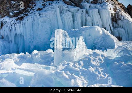 Pieces of ice lying on the ideal smooth ice of baikal with ice hummocks in the horizon. Sun is shining through the sides of ice cubes. Floes look Stock Photo