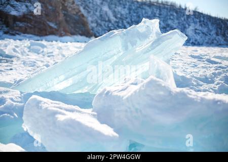 Pieces of ice lying on the ideal smooth ice of baikal with ice hummocks in the horizon. Sun is shining through the sides of ice cubes. Floes look Stock Photo