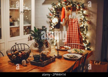 https://l450v.alamy.com/450v/2pw4h14/festive-winter-cozy-kitchen-interior-with-garlands-decorations-and-gifts-christmas-dinner-at-the-decorated-table-with-delicious-food-2pw4h14.jpg