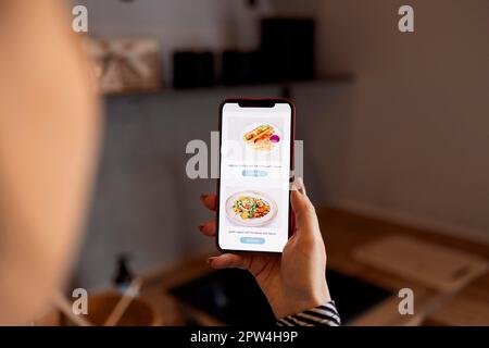 Happy shopper ordering from internet shop, using app on mobile phone for giving positive review to store. Woman using smartphone, ordering delivery Stock Photo