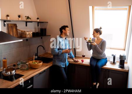 Side view of loving couple eating spaghetti while having romantic dinner together at home. Love, care, romance concept Stock Photo