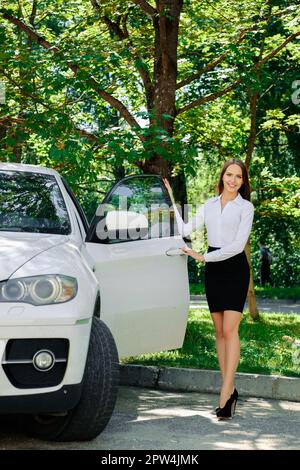 Beautiful girl opens the door of her car. Stock Photo