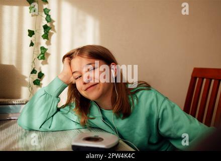 Teenage girl displaying CD and listening to music iin her room. Girl with retro player Stock Photo