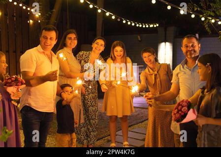 Group of wedding guests holding burning Bengal lights outdoors at wedding cocktail party. Happiness, joy and celebration concept Stock Photo