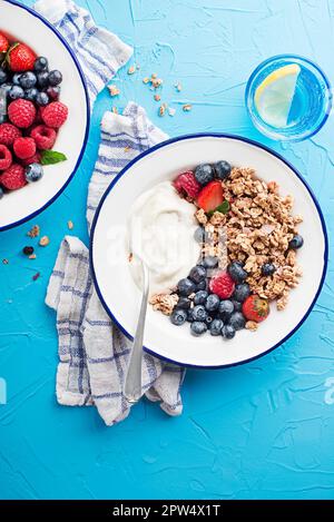 A plate of dry granola served with fresh berry fruit and yogurt. Oatmeal plate. Healthy food, diet. Top view. Stock Photo