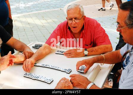 A group of senior Cuban-American men Enjoy a Game of Dominos on Calle Ocho in Miami Stock Photo