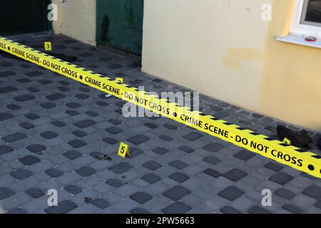 Crime scene tape for covering the area cordon. Yellow tape with blurred forensic law enforcement background in cinematic tone and copy space Stock Photo