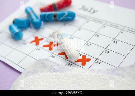 Aspects of women wellness in monthlies period. Menstrual pads and tampons on menstruation period calendar. Woman critical days, gynecological menstrua Stock Photo