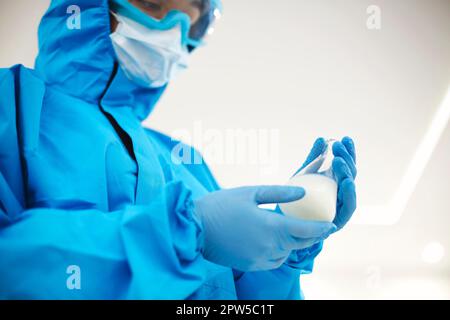 Female lab scientist examining samples in a test tube, working in an african american woman genetic laboratory wearing protected clothes Stock Photo