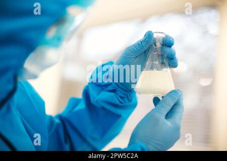 Female lab scientist examining samples in a test tube, working in an african american woman genetic laboratory wearing protected clothes Stock Photo