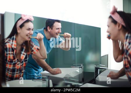 Happy Young brunette Couple Brushing Teeth In Bathroom, Loving Man and His Wife, Making Morning Hygiene Together, Bonding At Home, Selective Focus At Stock Photo