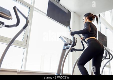 Attractive young athletic woman exercising in the gym. Doing cardio on the treadmill. Running on a treadmill Stock Photo