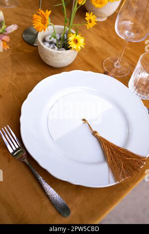 Wedding. Banquet. Chairs and a table for guests, decorated with candles, are served with cutlery and crockery and covered with yellow tablecloth. The Stock Photo