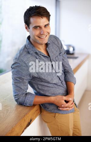 I was reminded that my blood type is Be positive. Portrait of a handsome young man leaning against his kitchen countertop Stock Photo