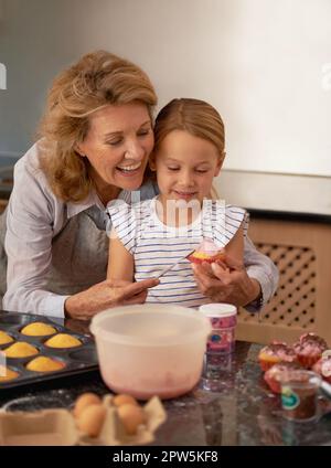 Those look amazing, honey. a little girl decorating cupcakes with the help of her grandmother Stock Photo