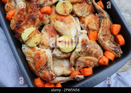 Roasted Rabbit Haunches in Pan with Stewed Vegetables on Rustic Wooden Table Surface . Stock Photo