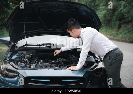 Asian businessman car broken breakdown, young stressed man having trouble car failure problem looking in frustration at failed engine in the morning, Stock Photo