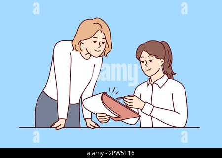 Woman manager sitting at table gives instructions to assistant using clipboard with working papers. Girl secretary stands near colleague and waits for Stock Photo