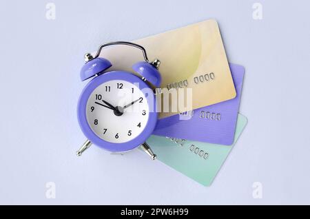 Small violet alarm clock lies on colored credit cards. The concept of modern fast online banking and funds transfer operations Stock Photo