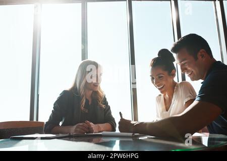 Their financial future is looking bright. a young couple meeting with a financial planner in a modern office. Stock Photo