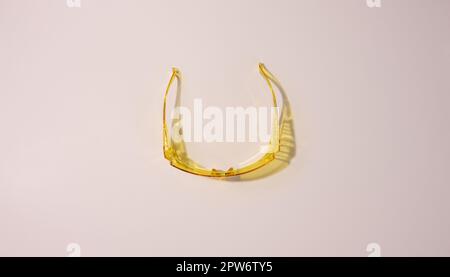 Yellow plastic protective goggles for workers on a beige background, top view Stock Photo