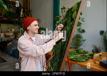 Young man designer creating floral composition at art studio. Skilled hipster florist working in workshop Stock Photo