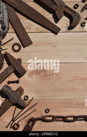 A set of old and rusty tools for handyman. A lot of obsolete household tools from rusty metal lie on a wooden table in the workshop. The concept of ho Stock Photo