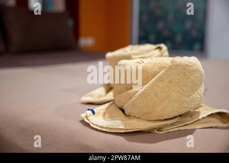 Yellow towel on bed decoration in bedroom interior, Freshly laundered fluffy towels, Towel in hotel room, Beautifully folded toiletries Stock Photo