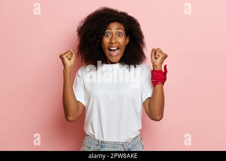 Happy dark skinned screaming woman, next to the pink all, she is celebrating her win. High quality photo Stock Photo