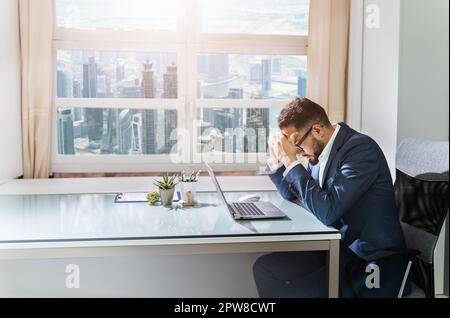 Upset Businessman Sitting In Office With Laptop On Desk Stock Photo
