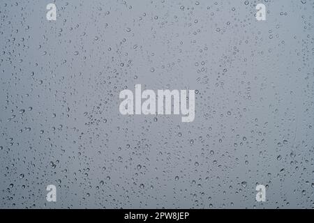 Rain drops on clear window glass with moody sky in the background. Stock Photo