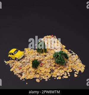Yellow Beetle climbs a mountain of cornflakes with trees on a black background. Minimal life style concept. Stock Photo
