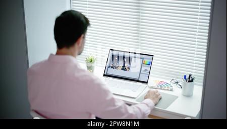 Photo Editor Working On Laptop At Desk Stock Photo
