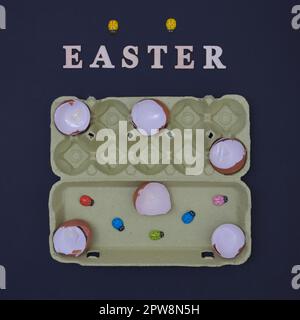 Egg shells lined up in an egg box and ladybugs on a black background with the inscription Easter. Minimalistic life style scene. Stock Photo