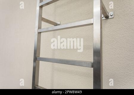 A fragment of a stainless steel ladder mounted on the wall of the building's facade. Stock Photo
