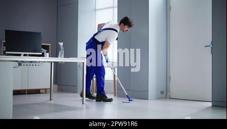 Portrait Of Happy Male Janitor Cleaning Floor At Office Stock Photo