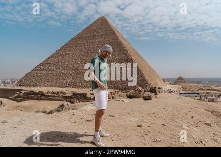 young man standing in the desert with Keops pyramid in the background. El Cairo. Egypt Stock Photo