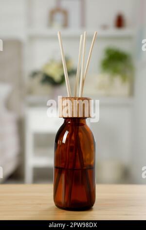 Aromatic reed air freshener on wooden table in room Stock Photo