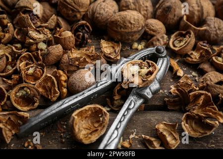 Walnuts, pieces of shells and nutcracker on wooden table Stock Photo