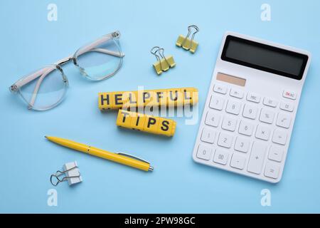 Flat lay composition with phrase Helpful Tips made of yellow cubes on light blue background Stock Photo