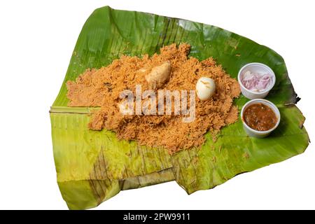 Hot chicken biryani with egg, raita and onion in banana leaf. A popular spicy non-vegetarian dish of India. Stock Photo