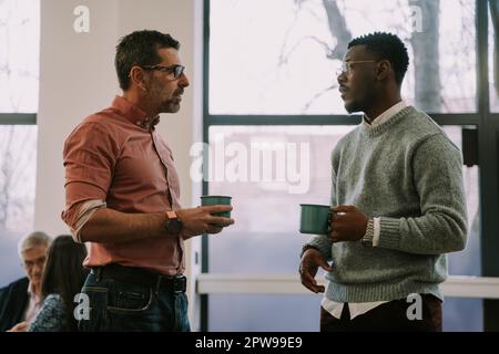 Two diverse coworkers making a plan for their next client on the internet at the office Stock Photo