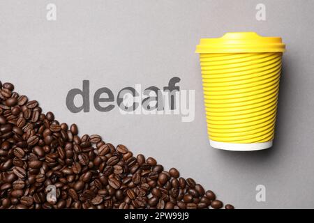 Word Decaf, coffee beans and takeaway paper cup on light grey ...