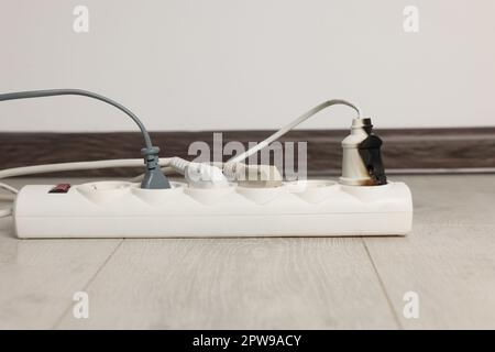 Burnt plug in power strip indoors. Electrical short circuit Stock Photo