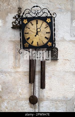 Old pendulum clock on the white stone wall Stock Photo