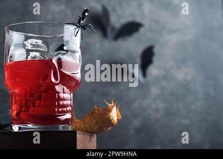 Halloween bloody cocktail. Bloody red cocktail glass goblet for Halloween and bottle form skull on dark backgrounds. Halloween party with candy eyes, Stock Photo