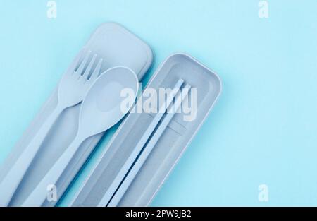 Plastic spoons, forks and chopsticks kit set on blue background. Stock Photo